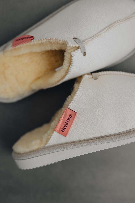 Close up View of Alys Eco Sheepskin Slippers with Heatons label detail on Concrete Surface
