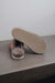 Alys Stone Sheepskin Slippers showing the bottom of the EVA sole on a Concrete Surface