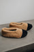 Side and top down view of soft-soled ballerina style curly beige sheepskin slipper with black toe point