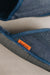 Close-up of navy,  denim covered, sheepskin mule slippers with a cork orange 'Heaton's' brand label displayed