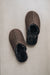 Pair of brown sheepskin slippers on a light grey background