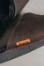 Close up of a pair of dark brown merino sheepskin men's mule slippers with an orange cork Heaton's label