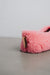 Close-up of a pink curly sheepskin slipper with a cork Heatons brand tag on a light grey stone background