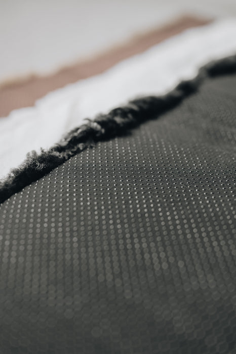 Close-up of a the rubber non
-slip underside of a black sheepskin pet bed