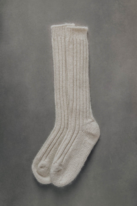 Ribbed beige natural merino wool sock on a light grey background.