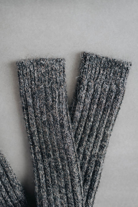 Ribbed brown natural merino wool sock on a light grey background - detail of ribbed sock neck