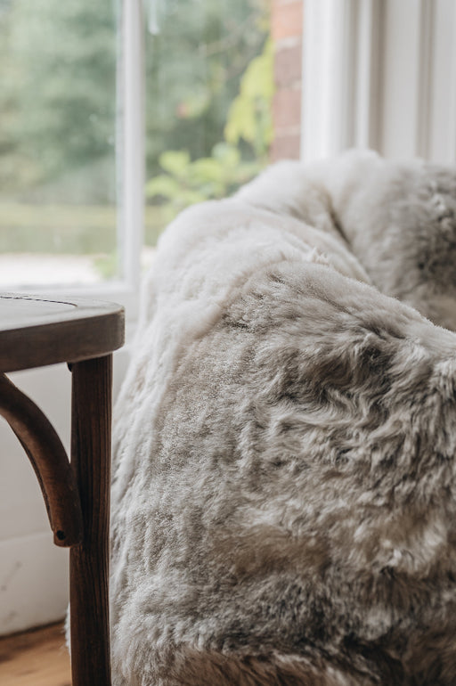 Close-up of a natural melange bean bag next to a wooden chair with a blurred background