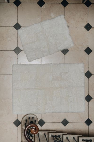 Two white designer sheepskin rugs on a tiled floor