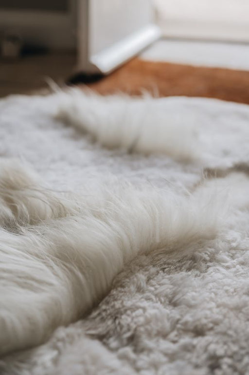 Close-up of a white designer rug of mixed lengths and tones with a blurred background