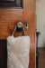 Oatmeal sheepskin draught excluder with leather handle hanging on a wooden door with a brass doorknob and keyhole.