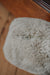 Close-up of the bottom of an oatmeal sheepskin door stop with a zipper on a wooden surface