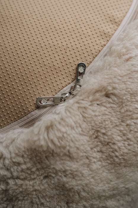 Close-up of a zipper on a beige fabric surface that is the bottom of a sheepskin beanbag.