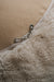 Close-up of a zipper on a beige fabric surface that is the bottom of a sheepskin beanbag.