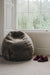 Wheat brown sheepskin bean bag chair next to a window with a pair of slippers on a carpeted floor.