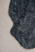 Close-up of a black smoke coloured sheepskin rug on a light coloured carpet