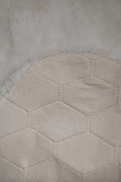 Close-up of a textured light fabric with a honeycomb pattern on the back / underside of a white sheepskin rug