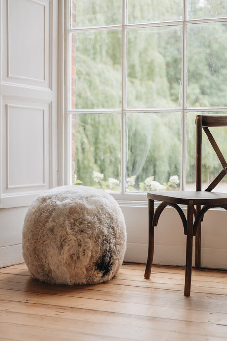 an Icelandic sheepskin footstool/pouffe in a melange colouration, grey and brown mixed tones in a natural pattern