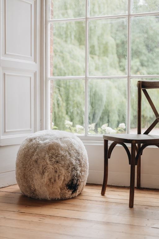 an Icelandic sheepskin footstool/pouffe in a melange colouration, grey and brown mixed tones in a natural pattern