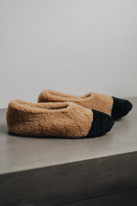 Side view of soft-soled ballerina style curly beige sheepskin slipper with black toe pointv