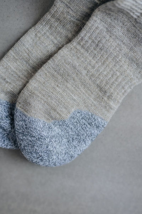 Close up view of Beige merino wool socks with blue toe post grey background