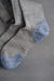 Fine knit beige merino wool socks with blue toes and cuffs on a grey background