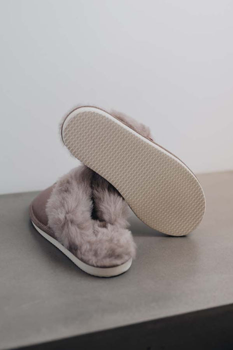 Gwen Stone Sheepskin Slippers showing the bottom of the EVA sole on a Concrete Surface