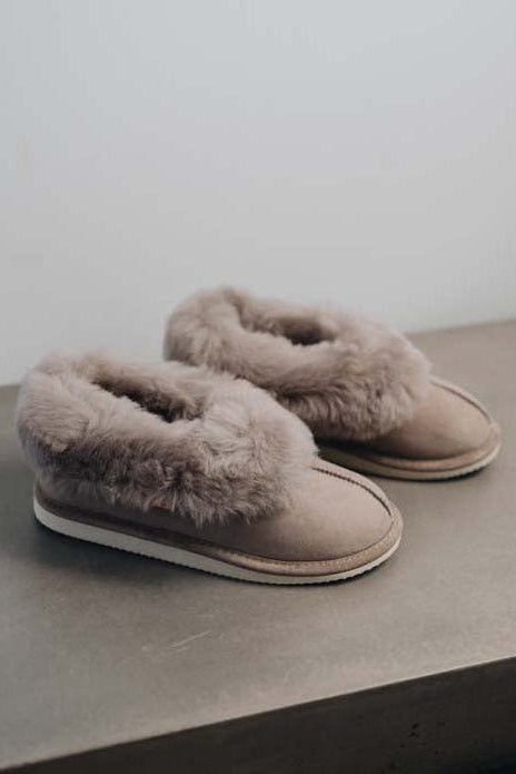 Side View of Ruby Stone Sheepskin Slippers on Concrete Surface