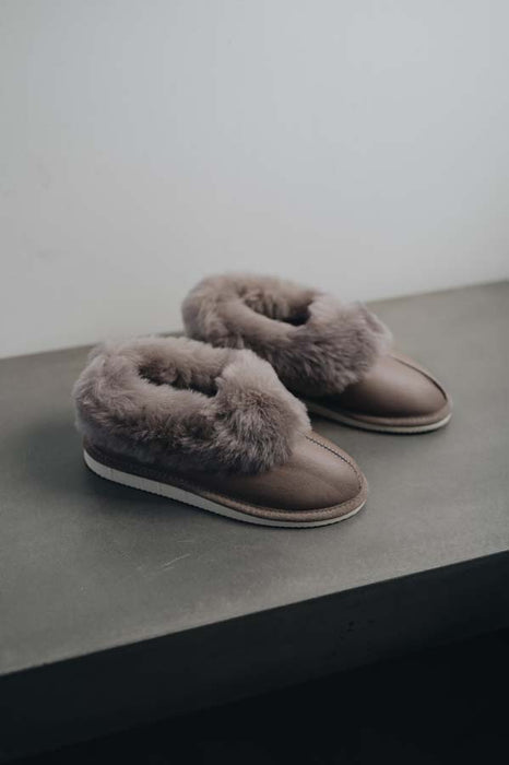 Side View of Ruby Walnut Sheepskin Slippers on Concrete Surface