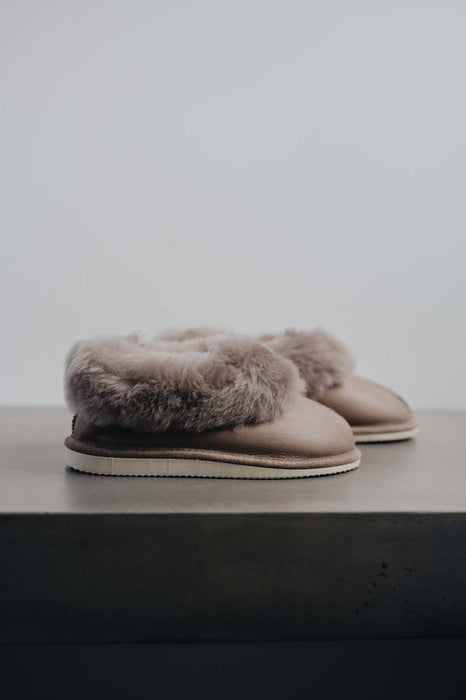 Side View of Ruby Walnut Sheepskin Slippers on Concrete Surface