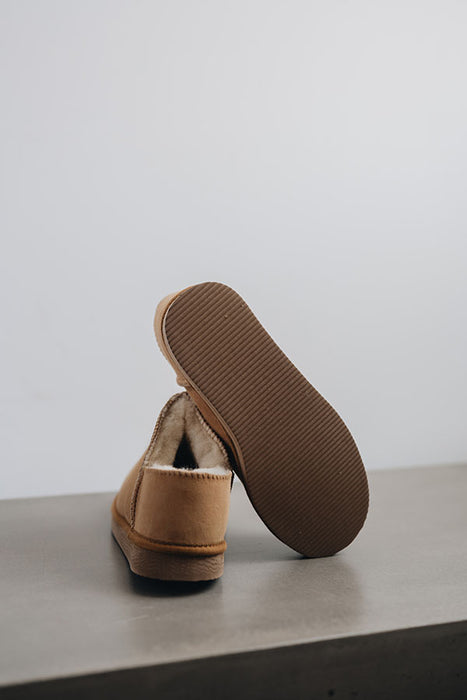 Cadi Mel Sheepskin Slippers showing the bottom of the EVA sole on a Concrete Surface
