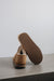 Cadi Mel Sheepskin Slippers showing the bottom of the EVA sole on a Concrete Surface