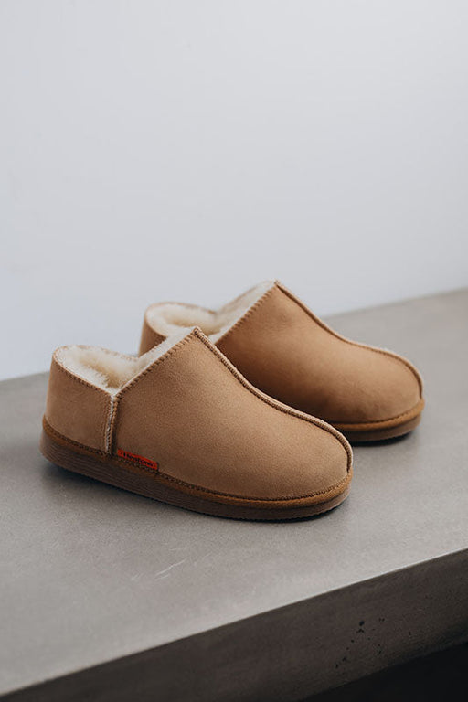 Side View of Cadi Mel Sheepskin Slippers on Concrete Surface