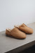 Side view of Cadi Womens Sheepskin Slippers in Tabac on a Concrete Surface