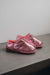 Side View of Cadi Metallic Pink Sheepskin Slippers on Concrete Surface