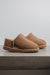 Side view of Cadi Taupe Sheepskin Slippers on Concrete Surface