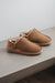 Side view of Cadi Taupe Sheepskin Slippers on Concrete Surface