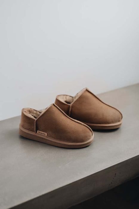 Side view of Cadi Taupe Sheepskin Slippers on a Concrete Surface