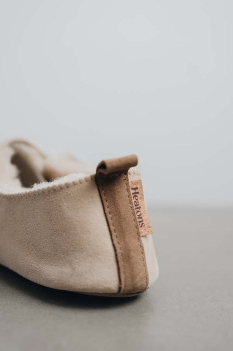 Rear view of Grace, a light soft-soled sheepskin slipper showing the detail of the suede tag and label.