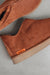 Close up of rust coloured ankle-high sheepskin slipper with orange cork label showing the Heatons brand