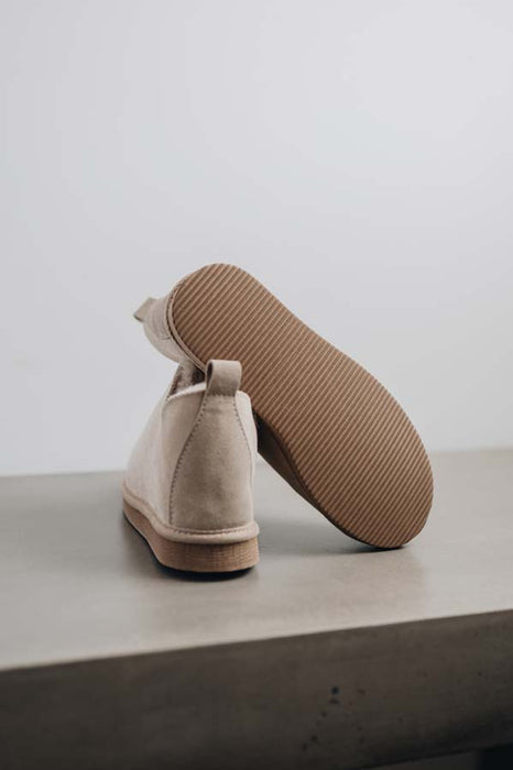 Close up of vanilla coloured ankle-high sheepskin slipper showing the ribbed underside of the PVA sole