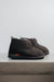 Side view of Noah dark brown Sheepskin Slippers on Concrete Surface