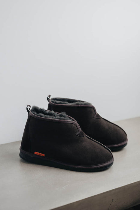 Profile view of Noah Dark Brown Sheepskin Slippers on Concrete Surface