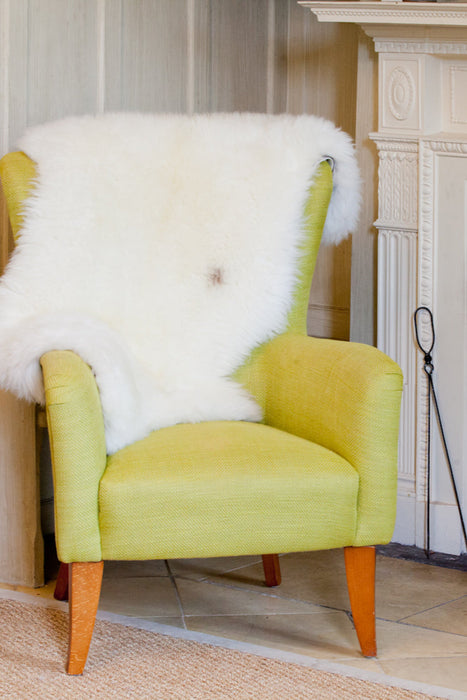 Fireside  appeal - All Natural British Sheepskin Rugs - Natural white nestled in the back of a high backed  chair by the fire