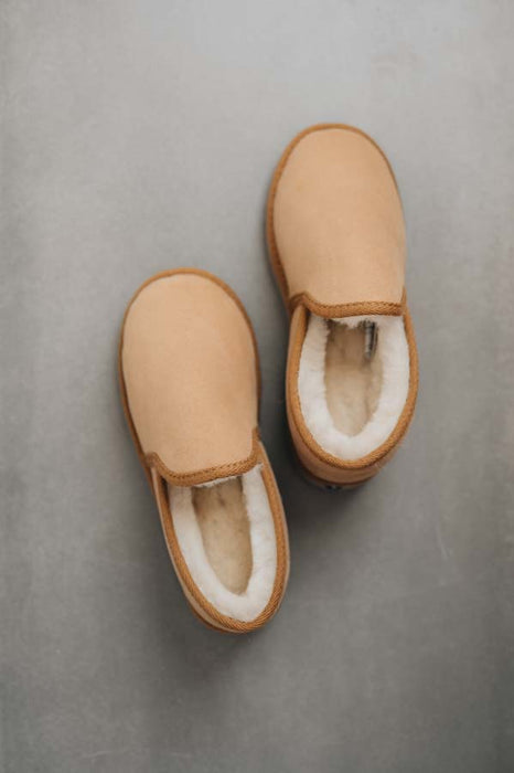 Birds eye view of Reggie men's Sheepskin Slippers on a Concrete Surface. 