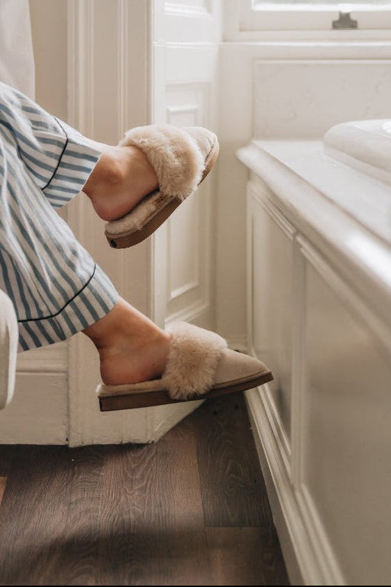 Womens Sheepskin Slippers Mule Veronica in vanilla colour. cross legged on a chair arm