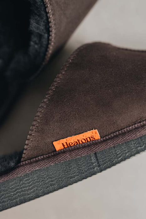 Close up of brown coloured slip on style sheepskin slipper with orange cork label showing the Heatons brand