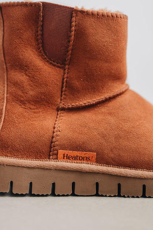 Close-up of a rust coloured sheepskin boot with 'Heatons' branding and a chunky sole.