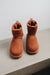 Front view of a rust coloured sheepskin boot with pull tab on the back