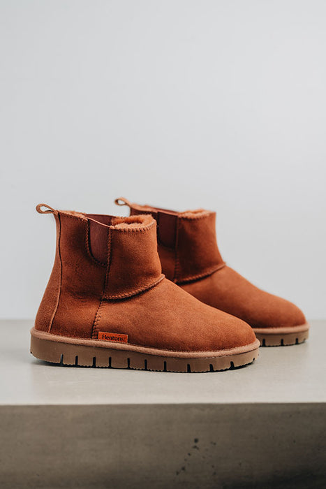 Profile view of a rust coloured sheepskin boot with 'Heatons' branding and a chunky sole.