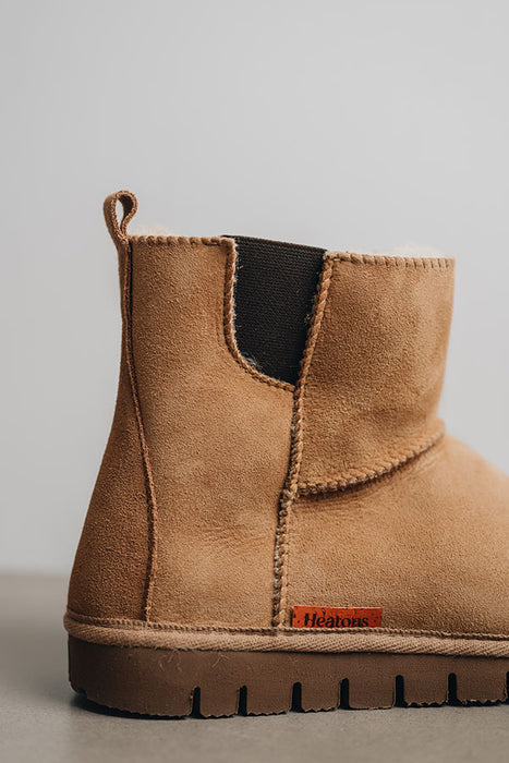 Close-up of a the back of a tan coloured sheepskin boot with 'Heatons' branding and a chunky sole.